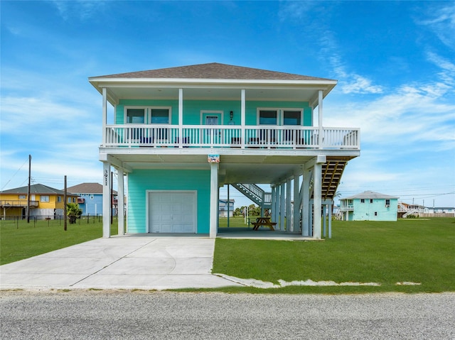 raised beach house with a front yard, covered porch, a garage, and a carport