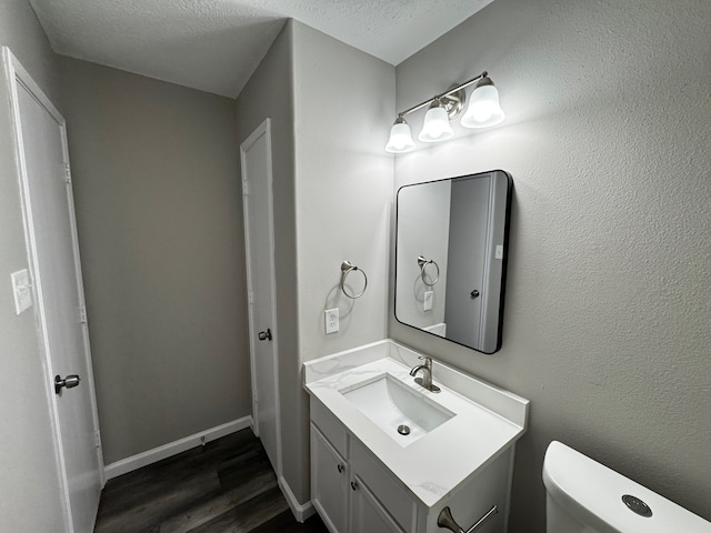 bathroom featuring vanity, toilet, a textured ceiling, and hardwood / wood-style floors