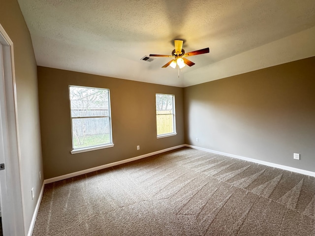 carpeted spare room featuring a textured ceiling and ceiling fan