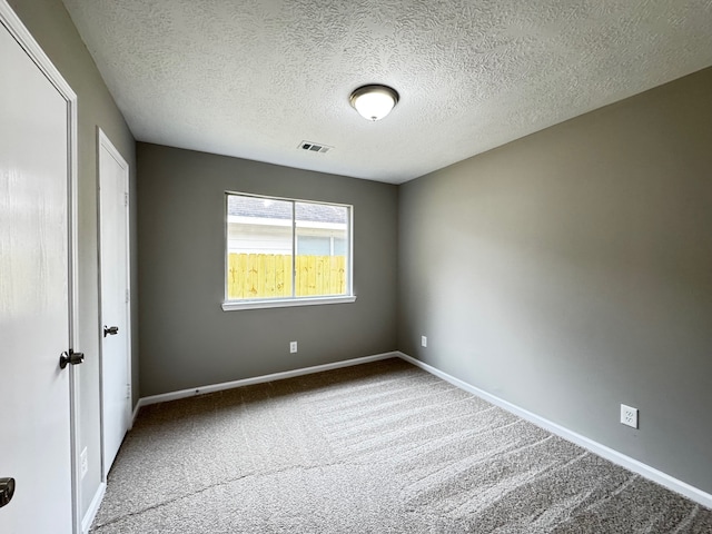 carpeted empty room featuring a textured ceiling