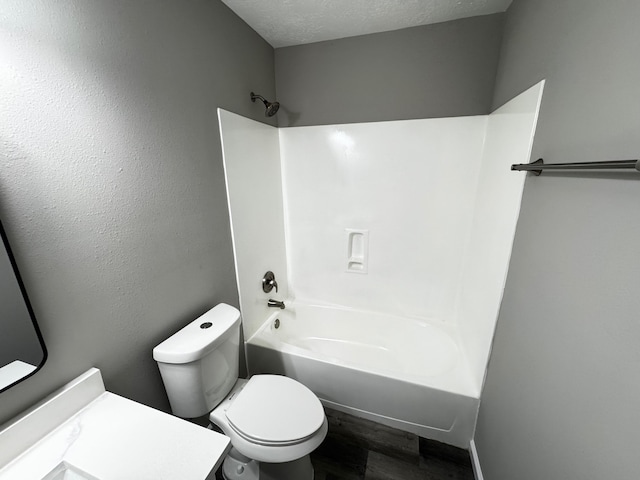 full bathroom with toilet, hardwood / wood-style floors,  shower combination, vanity, and a textured ceiling