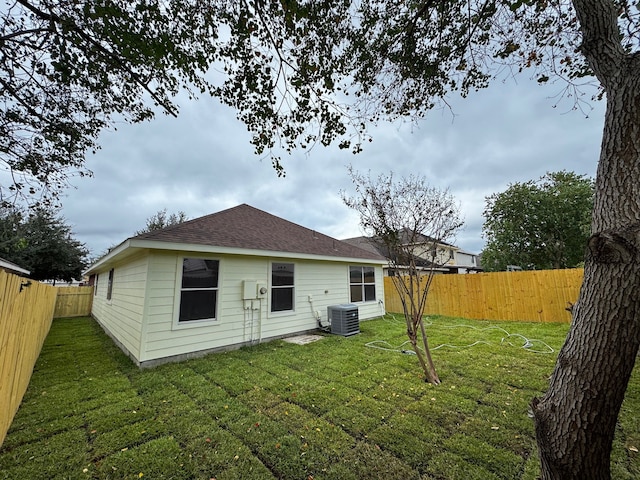 rear view of property featuring a lawn and central AC unit