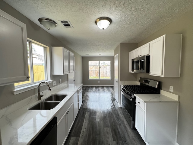 kitchen with dark hardwood / wood-style floors, stainless steel appliances, sink, white cabinets, and light stone counters