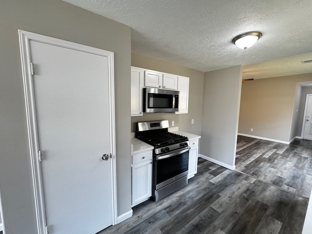 kitchen with a textured ceiling, white cabinetry, stainless steel appliances, and dark hardwood / wood-style floors