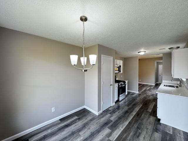 unfurnished dining area featuring sink, a textured ceiling, dark hardwood / wood-style flooring, and an inviting chandelier