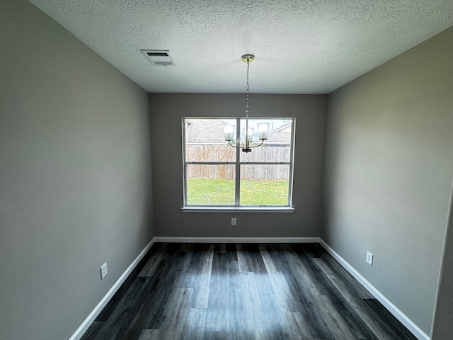 unfurnished dining area featuring an inviting chandelier, dark hardwood / wood-style floors, and a textured ceiling