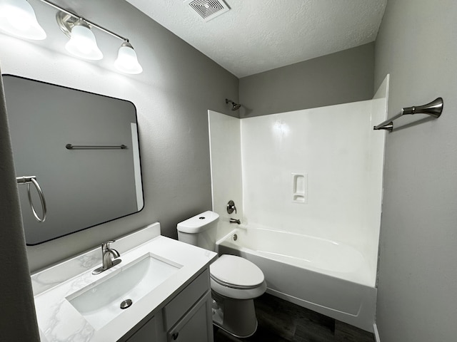 full bathroom featuring toilet, wood-type flooring, vanity, washtub / shower combination, and a textured ceiling