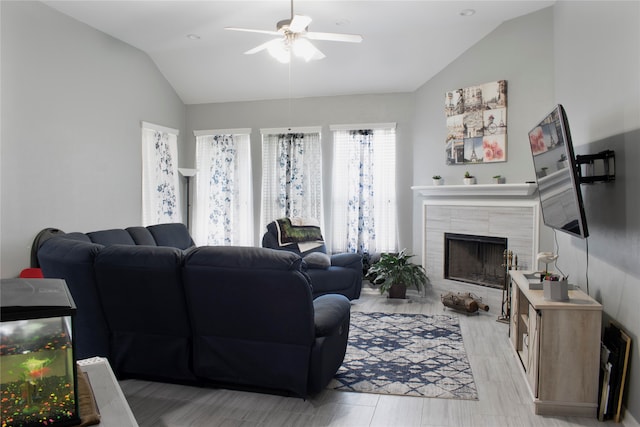 living room with ceiling fan, lofted ceiling, a fireplace, and light hardwood / wood-style flooring