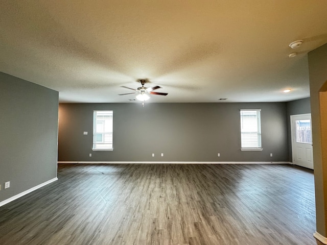 spare room featuring a textured ceiling, dark hardwood / wood-style floors, a wealth of natural light, and ceiling fan