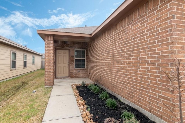 entrance to property featuring a patio and a lawn