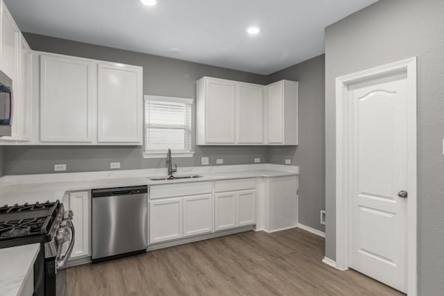 kitchen featuring white cabinetry, appliances with stainless steel finishes, sink, and light hardwood / wood-style flooring