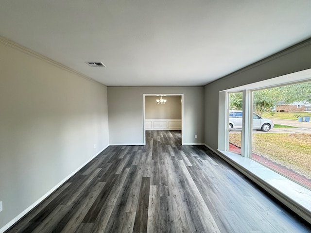 empty room with ornamental molding, dark wood-type flooring, and a notable chandelier