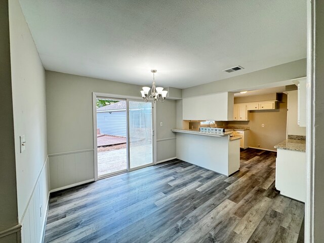 kitchen featuring white cabinetry, kitchen peninsula, an inviting chandelier, and dark hardwood / wood-style flooring