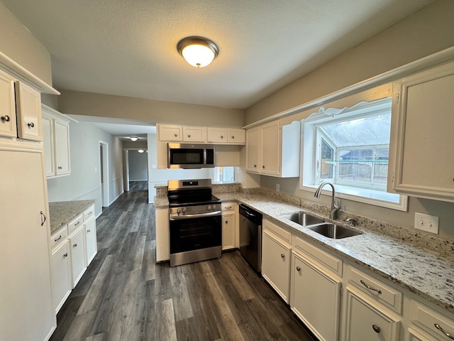 kitchen with sink, light stone countertops, white cabinets, appliances with stainless steel finishes, and dark hardwood / wood-style flooring