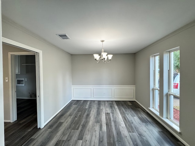 unfurnished dining area featuring an inviting chandelier, ornamental molding, and dark hardwood / wood-style flooring