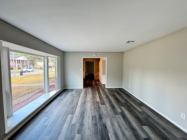 empty room with ornamental molding and dark hardwood / wood-style flooring