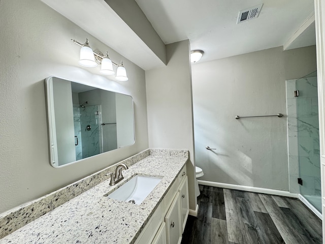 bathroom featuring toilet, hardwood / wood-style floors, vanity, and a shower with door