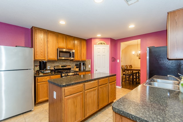 kitchen with decorative backsplash, light tile patterned floors, appliances with stainless steel finishes, a kitchen island, and sink