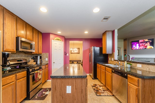 kitchen with stainless steel appliances, sink, a center island, light tile patterned flooring, and tasteful backsplash