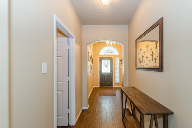 doorway featuring a notable chandelier, a textured ceiling, and dark hardwood / wood-style flooring