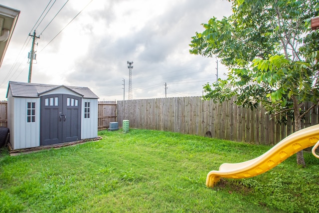 view of yard featuring central air condition unit, a shed, and a playground