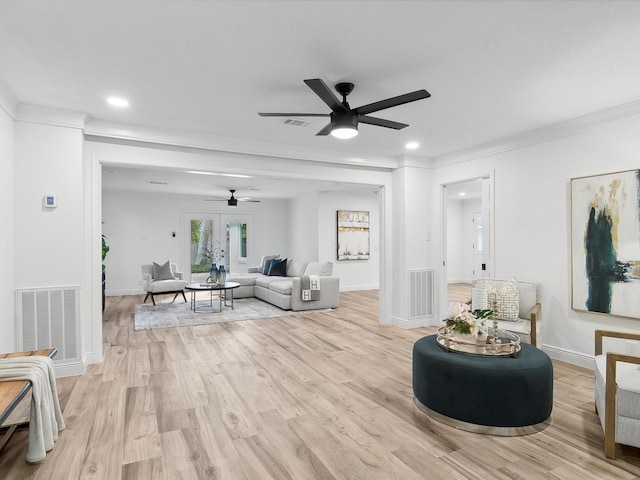 living room with light hardwood / wood-style floors, ornamental molding, and ceiling fan