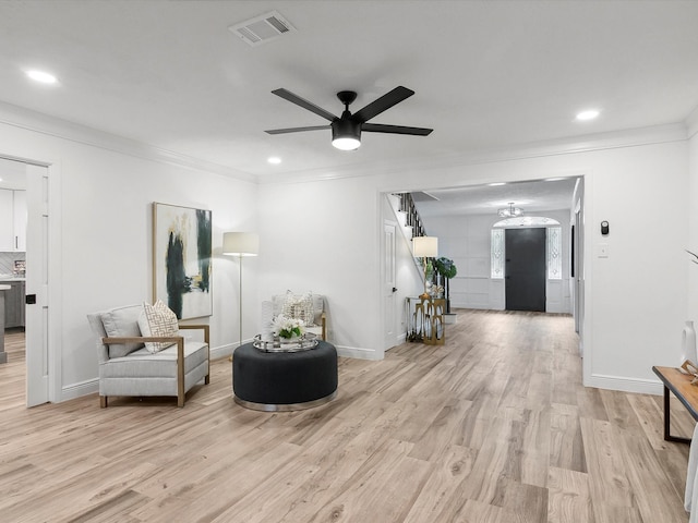 living area with crown molding, light hardwood / wood-style floors, and ceiling fan