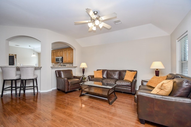 living room featuring ceiling fan, vaulted ceiling, and light wood-type flooring