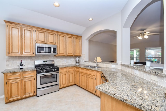 kitchen with sink, ceiling fan, light tile patterned floors, light stone counters, and stainless steel appliances