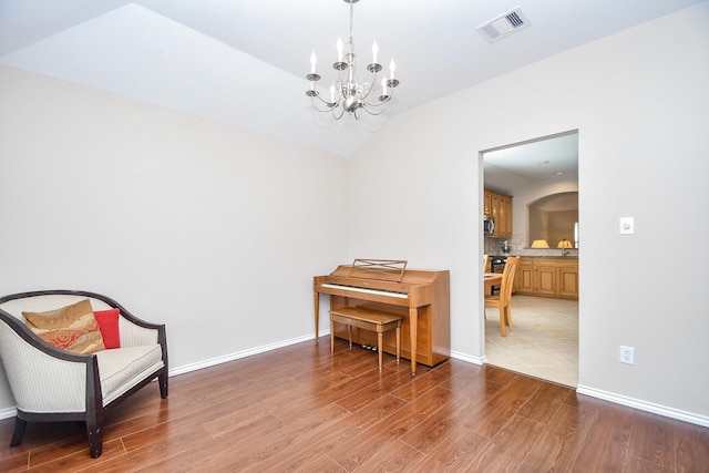 sitting room featuring wood-type flooring, vaulted ceiling, and an inviting chandelier