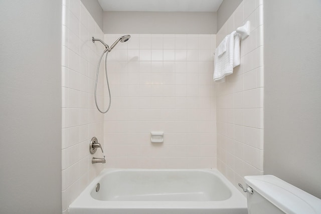 bathroom with tiled shower / bath combo and toilet