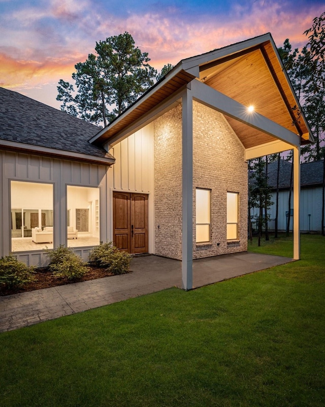 back house at dusk featuring a lawn