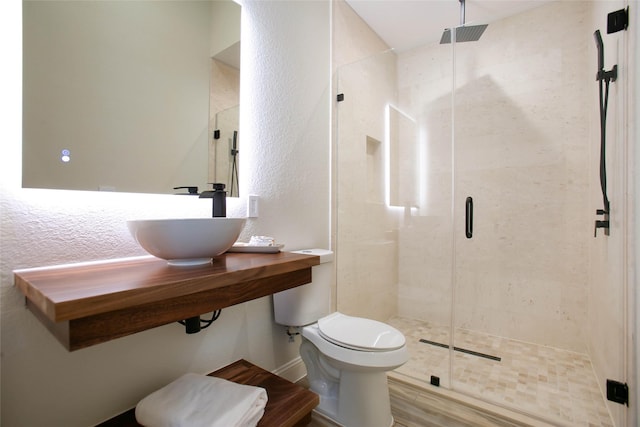 bathroom with hardwood / wood-style floors, toilet, a shower with door, and sink