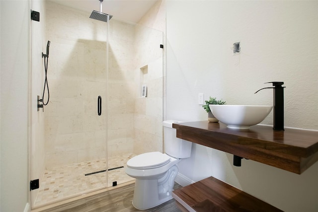 bathroom featuring hardwood / wood-style flooring, toilet, a shower with door, and sink