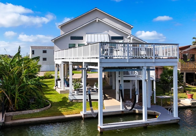 rear view of property featuring a carport, a lawn, and a deck with water view