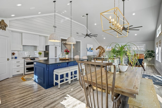 dining space with ceiling fan, high vaulted ceiling, and light wood-type flooring