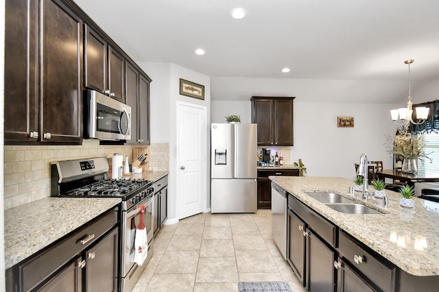 kitchen featuring appliances with stainless steel finishes, backsplash, decorative light fixtures, light stone counters, and an inviting chandelier