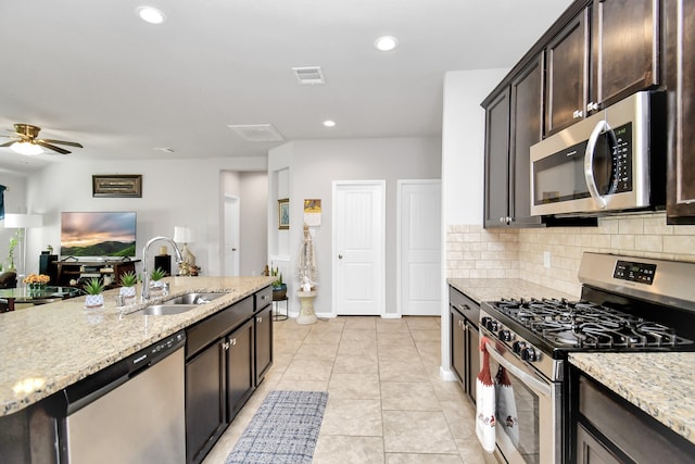 kitchen featuring light stone countertops, appliances with stainless steel finishes, sink, dark brown cabinets, and ceiling fan