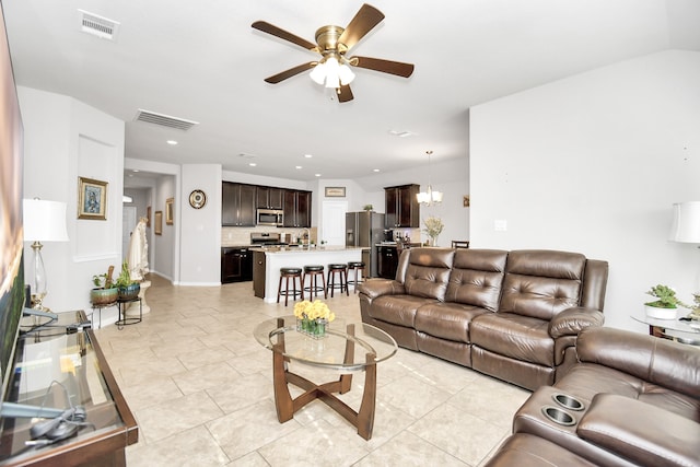 tiled living room featuring ceiling fan with notable chandelier