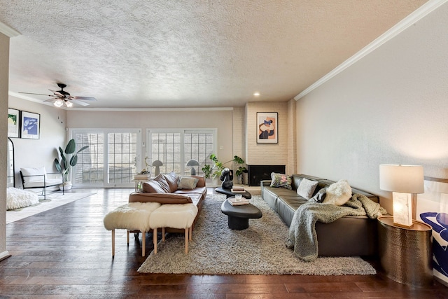 living room featuring ceiling fan, dark hardwood / wood-style flooring, a textured ceiling, a fireplace, and crown molding