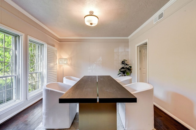 dining space featuring dark wood-type flooring, ornamental molding, and a textured ceiling