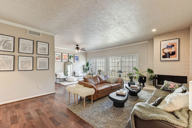 living room with ceiling fan, a textured ceiling, dark hardwood / wood-style flooring, and ornamental molding