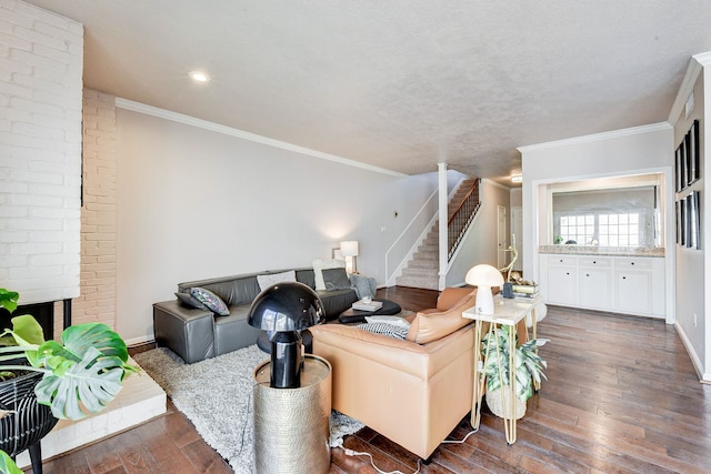 living room with dark wood-type flooring, ornamental molding, a textured ceiling, and a brick fireplace