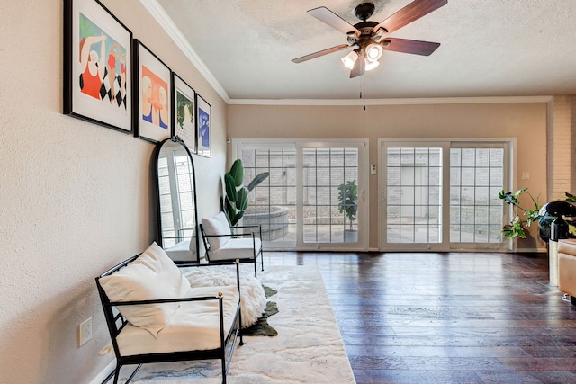 living area with ceiling fan, crown molding, a textured ceiling, and hardwood / wood-style floors