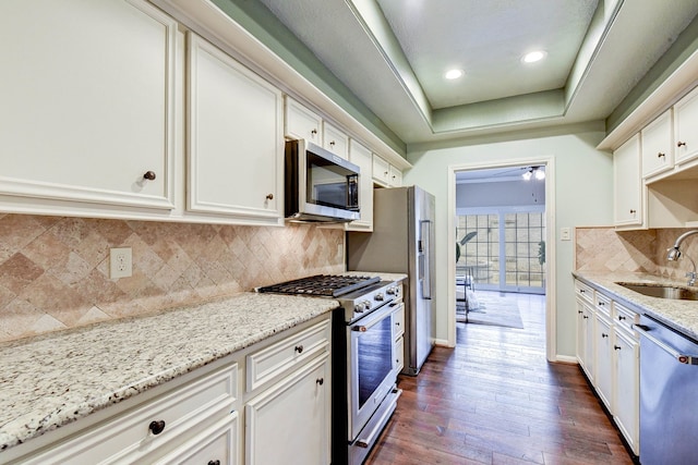 kitchen featuring light stone countertops, sink, appliances with stainless steel finishes, dark hardwood / wood-style flooring, and white cabinetry