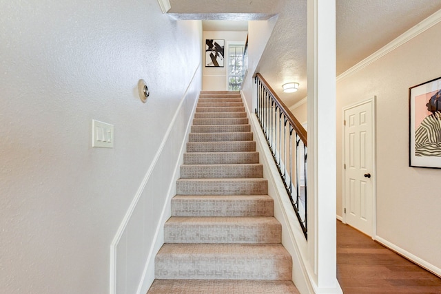 staircase featuring hardwood / wood-style floors and crown molding