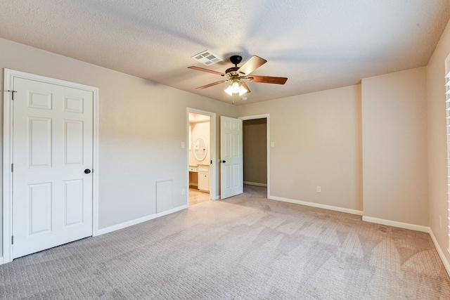 unfurnished bedroom with connected bathroom, light carpet, a textured ceiling, and ceiling fan