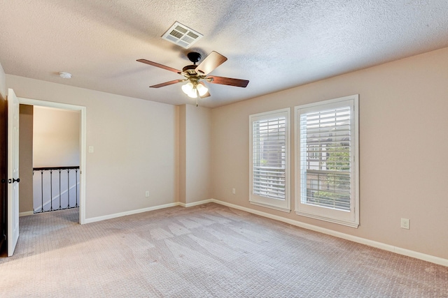 carpeted spare room with ceiling fan and a textured ceiling