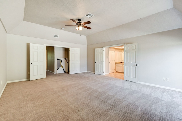 unfurnished bedroom with ceiling fan, light carpet, a textured ceiling, and ensuite bathroom