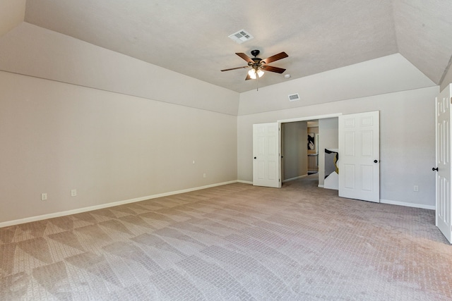 interior space with lofted ceiling, light carpet, a textured ceiling, and ceiling fan